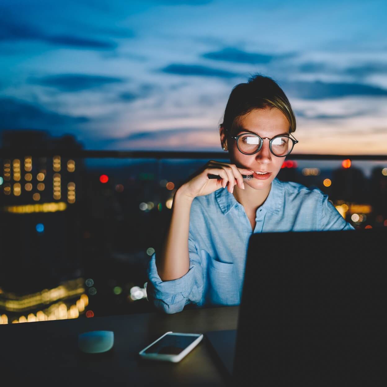 Woman looking at laptop with city in background